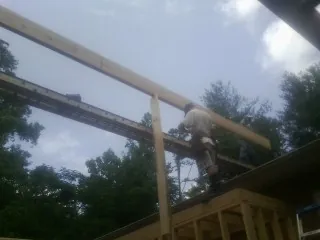 Carpenter setting a ridge beam over a new addition frame — Ice Dam Removal by Roofing Brothers in Delanson