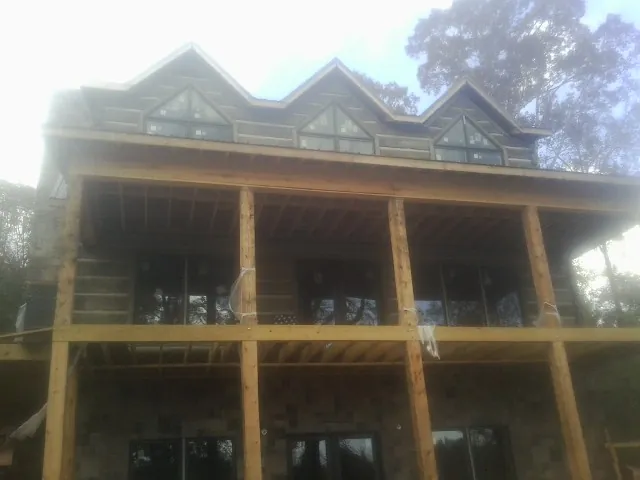Dormers and porch framing on a large log home under construction — Roof Coating work by our crew in Delanson